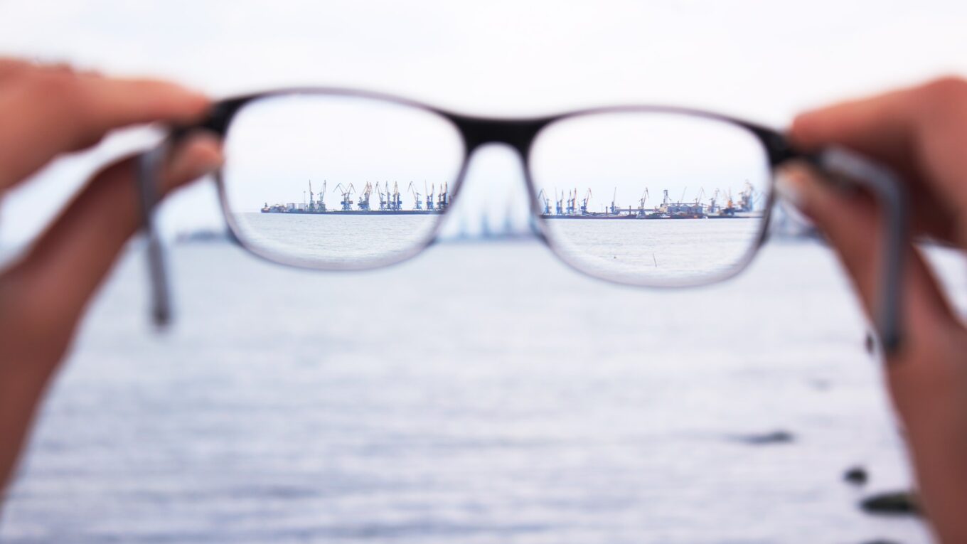 Glasses being held up to show a coastal view in focus