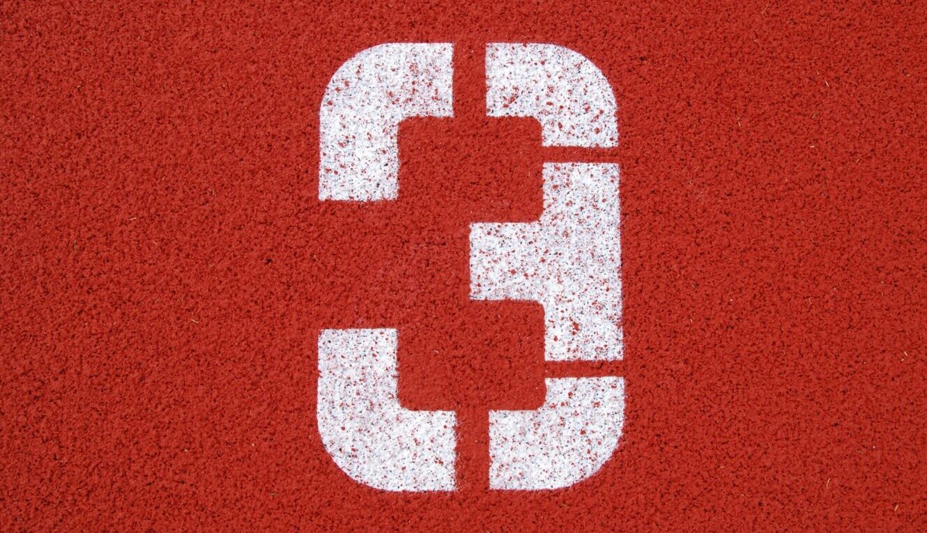 White number three spray painted onto a red athletic track