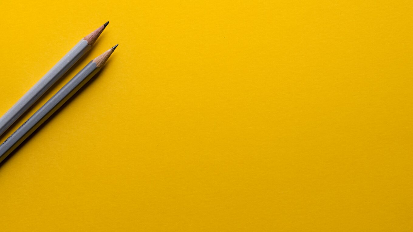 Two grey pencils on a yellow desk